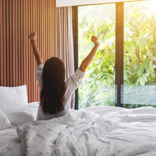 rear-view-woman-stretching-after-waking-up-morning-looking-beautiful-nature-view-outside-bedroom-window